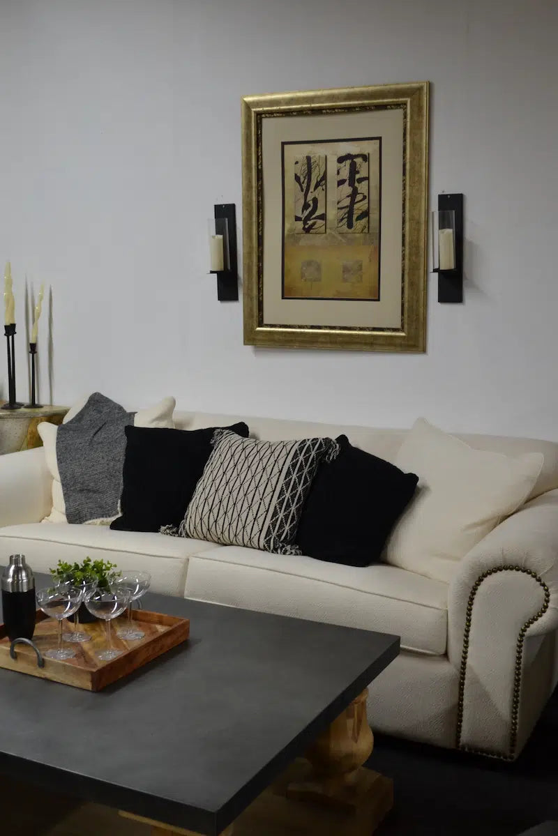 Living room with a cream sofa, decorative pillows, a zinc top coffee table, and wall art.