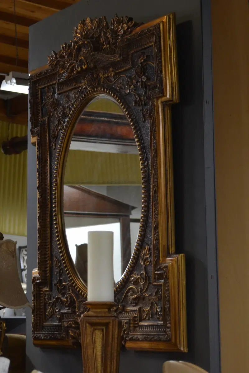 Decorative gold-framed mirror on a dark wall